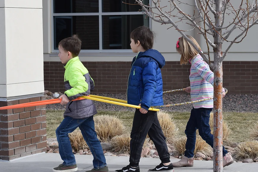 Three students walking with hula hoops