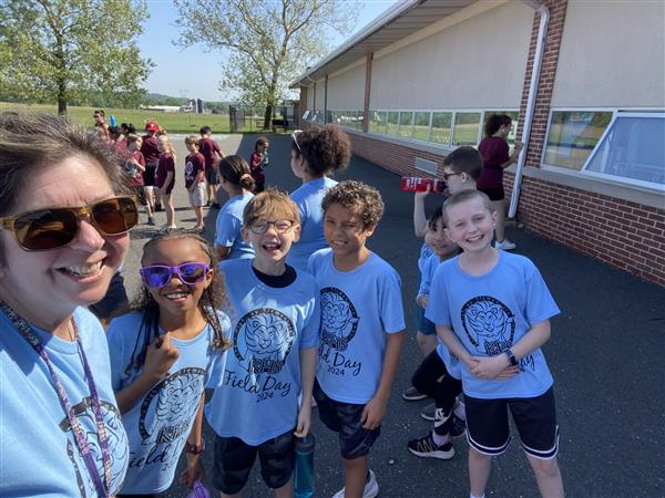 Woman in blue shirt and sunglasses posing with kids.