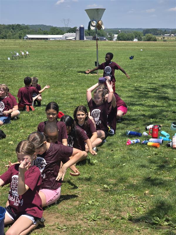 Children sitting on grass in field.