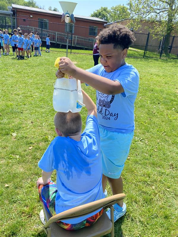 Two boys having fun with a bucket of water.