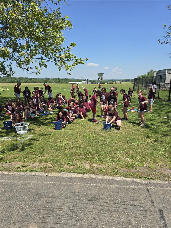 A group of people in maroon shirts sitting on the grass.