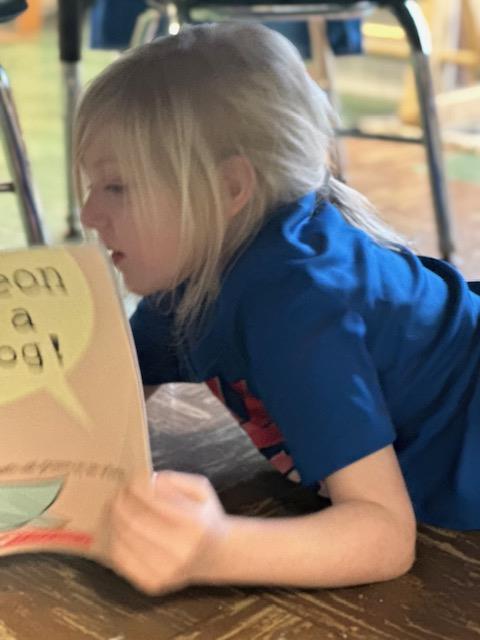 A young girl sitting on the floor, reading a book.