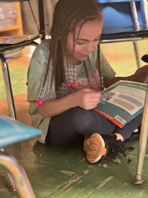 A young girl sitting on the floor reading a book.