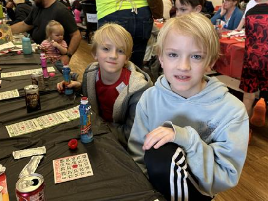 Two kids playing a board game at a table.