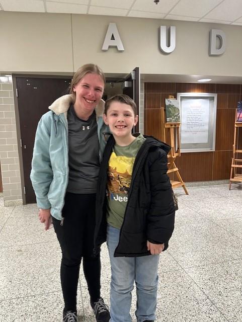 Woman and boy standing in front of sign.