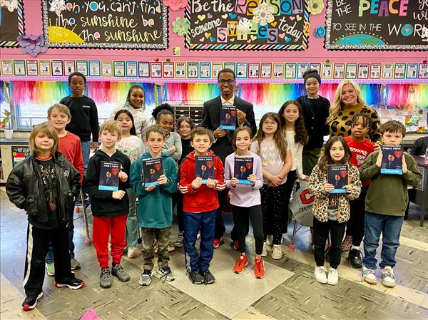 Children holding books in a classroom.