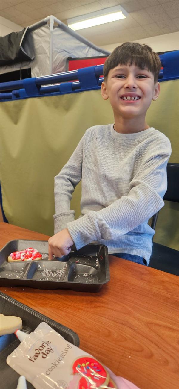 A smiling boy holding a tray of cookies.