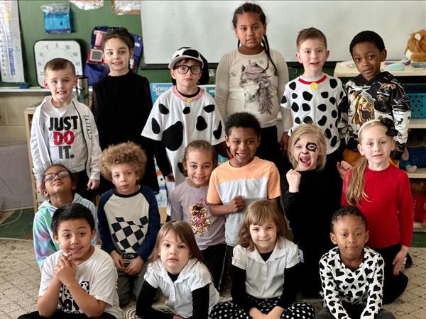  Children wearing cow print outfits, smiling and playing together.