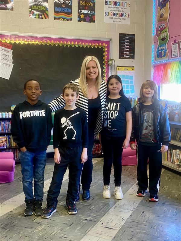 A woman and children smiling for a photo in a classroom.