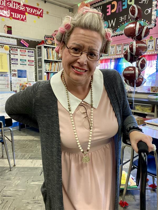 Woman in pink dress and glasses smiling for photo.