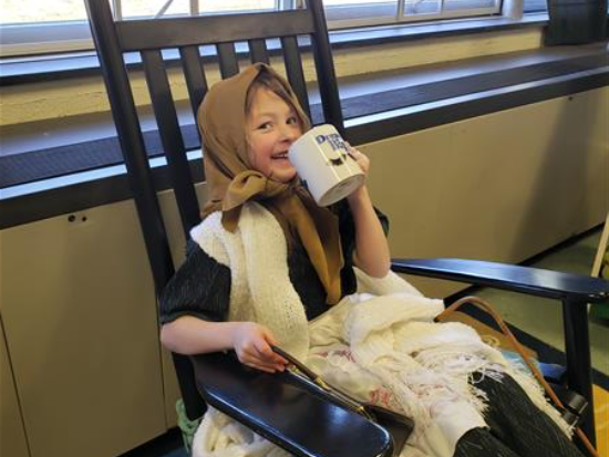  A young girl reading a book in a rocking chair.