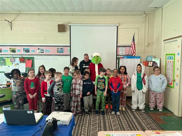 Children in pajamas standing in front of a classroom.