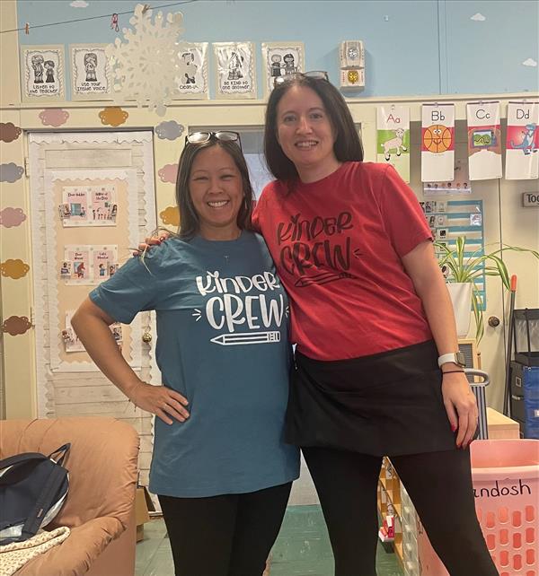 Two women in classroom wearing t-shirts.