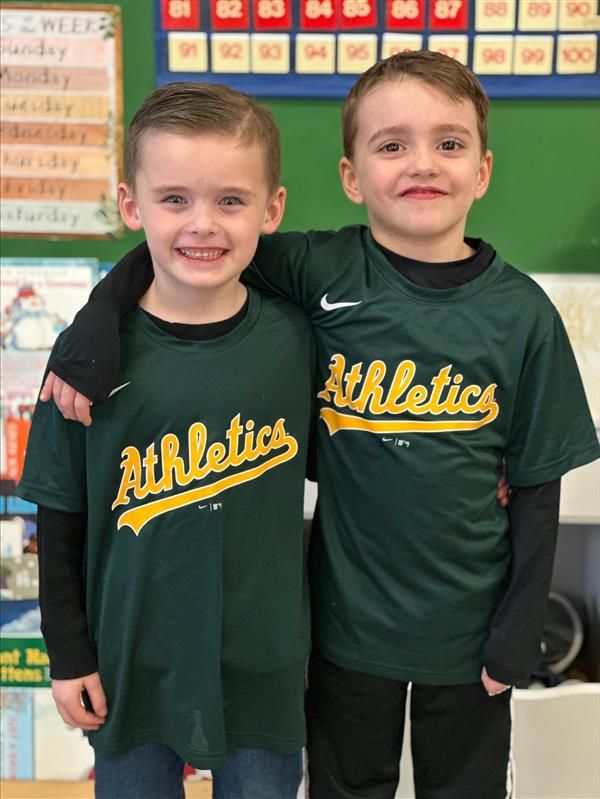 Two young boys in green athletics shirts.