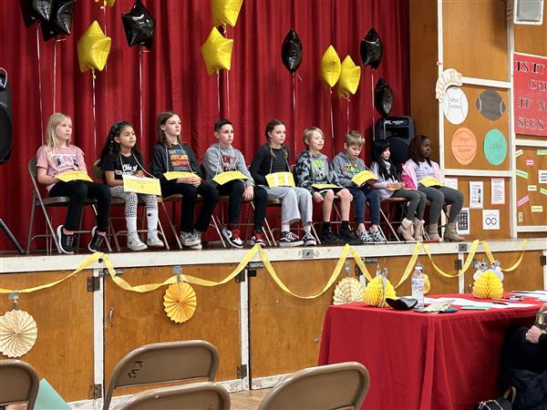 Children sitting at a table with colorful balloons.