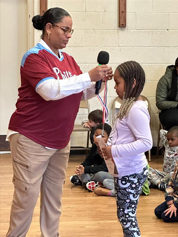 A woman giving an award to a child