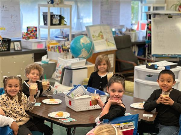 Children sitting at a table eating food.