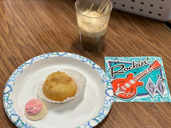 A plate with a cup of coffee and a cupcake on it.