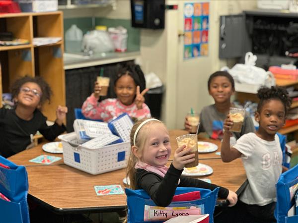 Children sitting at a table eating food.