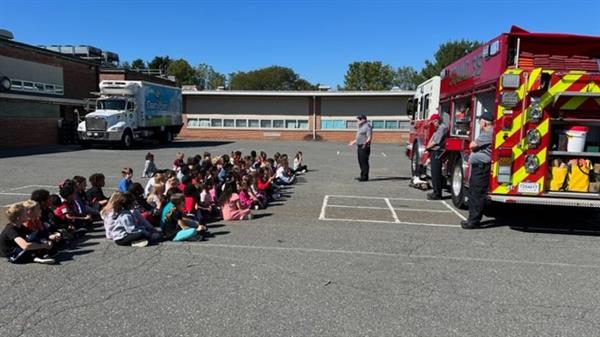 Children sitting in front of a fire truck.