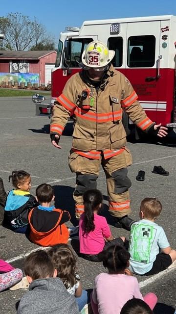 Children sitting in front of a fire truck.