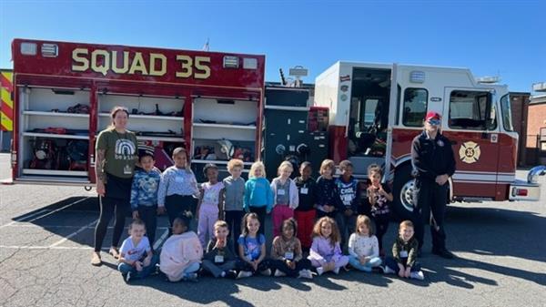 Children sitting in front of a fire truck.