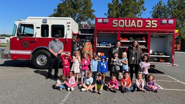 Children sitting in front of a fire truck.