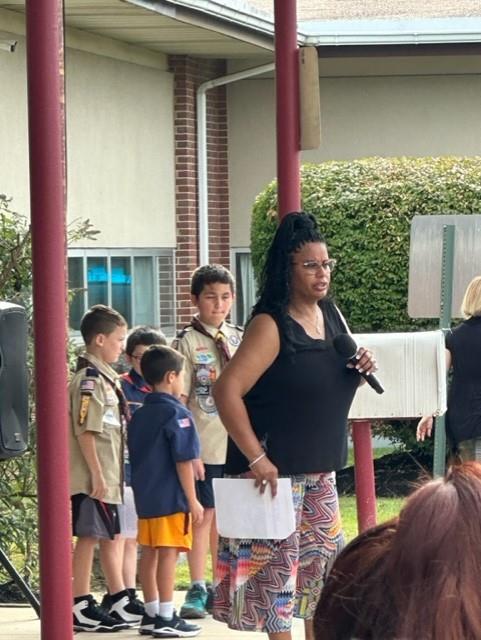 A woman in a black shirt talking to a group of kids.