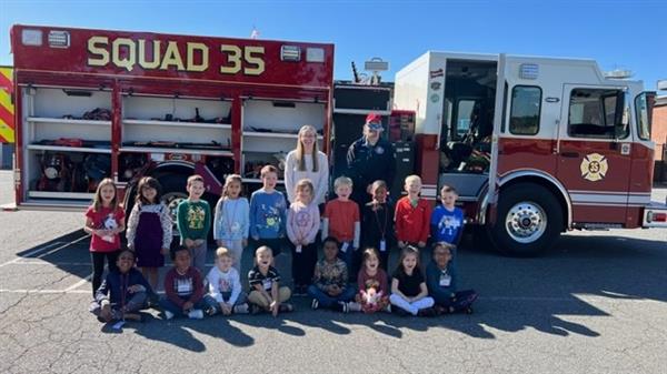 Children sitting in front of a fire truck.