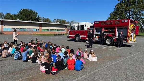 Children sitting in front of a fire truck.