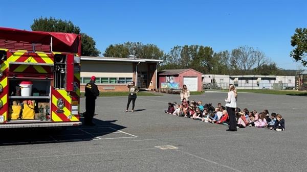 Children sitting in front of a fire truck.