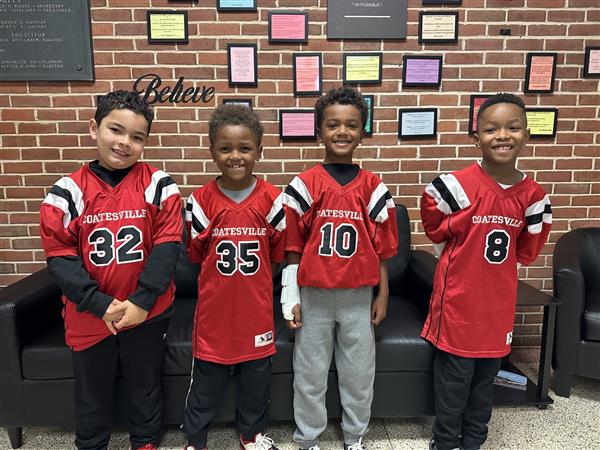 Three young boys in football jerseys smiling for a photo.