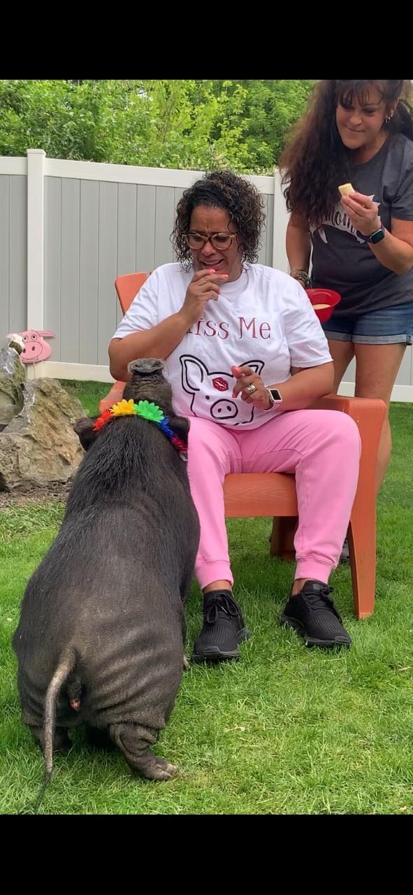 Woman in white shirt feeding a pig on a farm.