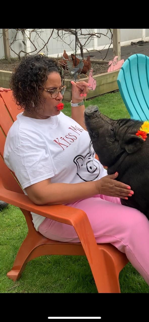 Woman in white shirt feeding a pig on a farm.