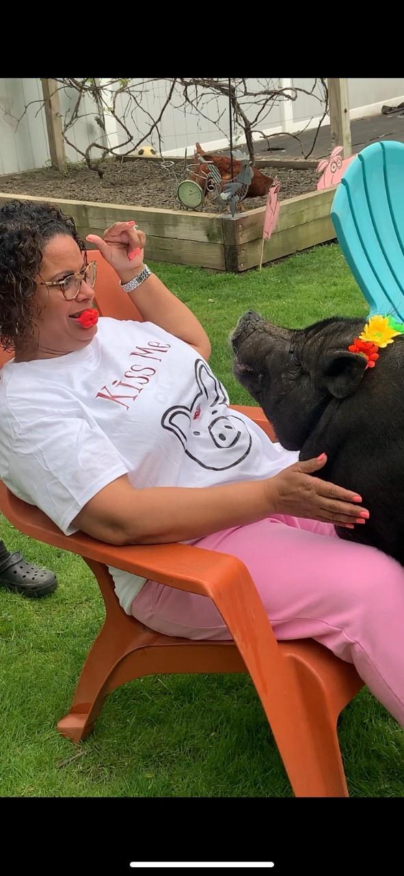 Woman in white shirt feeding a pig on a farm.