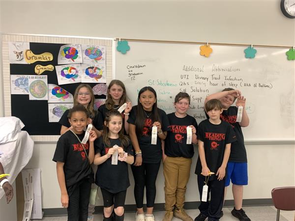 Happy children in black shirts displaying their trophies with big smiles.