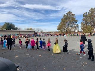 Children in costumes parade down the street during Halloween.