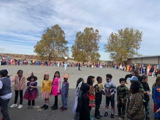 Children in costumes parade down the street during Halloween.