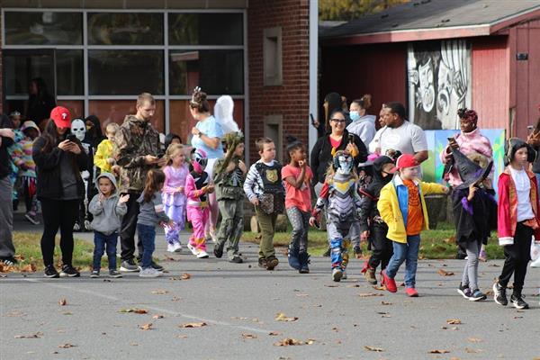 Children in costumes parade down the street during Halloween.