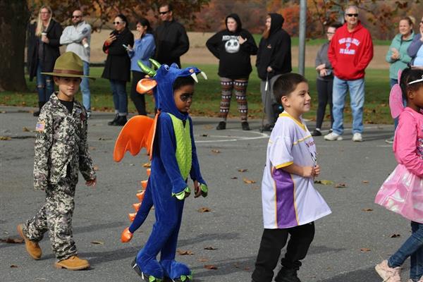 Children in costumes parade down the street during Halloween.