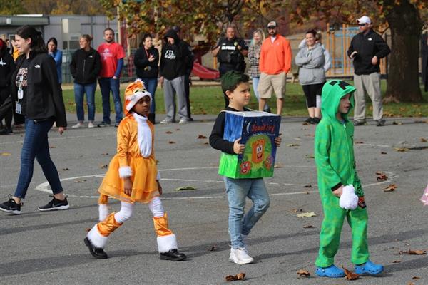 Children in costumes parade down the street during Halloween.