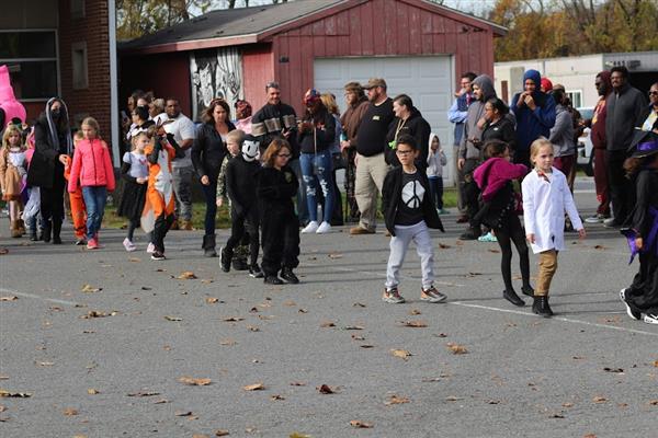 Children in costumes parade down the street during Halloween.