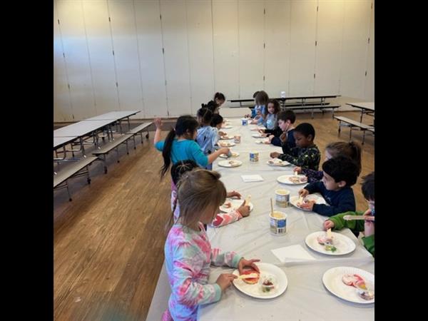 Children enjoying a meal at a spacious table in a bright room.