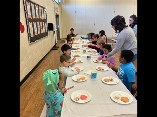 Children enjoying a meal at a spacious table in a bright room.