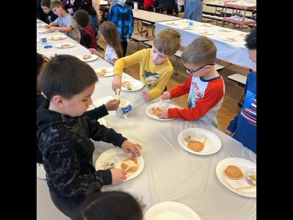 Children enjoying a meal at a spacious table in a bright room.