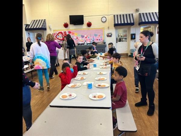 Children enjoying a meal at a spacious table in a bright room.