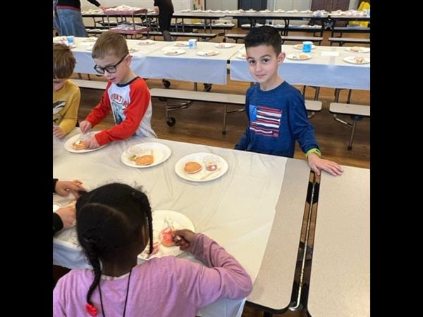 Children enjoying a meal at a spacious table in a bright room.