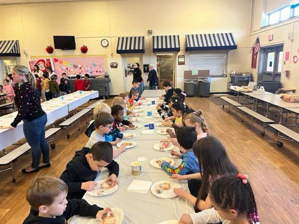 Children enjoying a meal at a spacious table in a bright room.