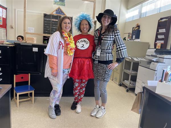 Three women in colorful costumes smiling for a photo.