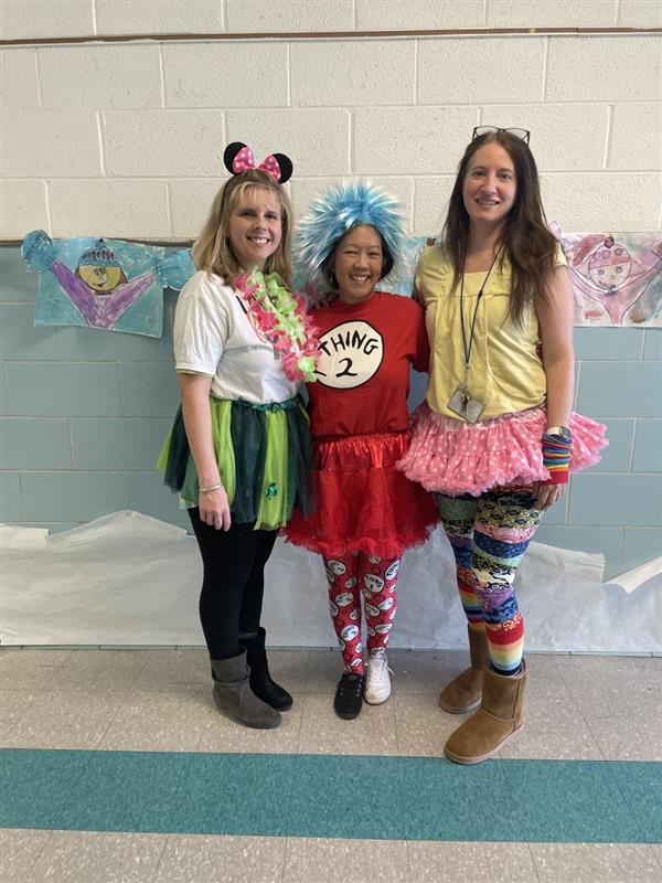 Three women in colorful costumes smiling for a photo.